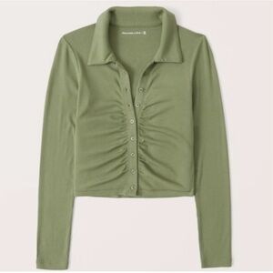 Green long-sleeved polo top, slightly cropped